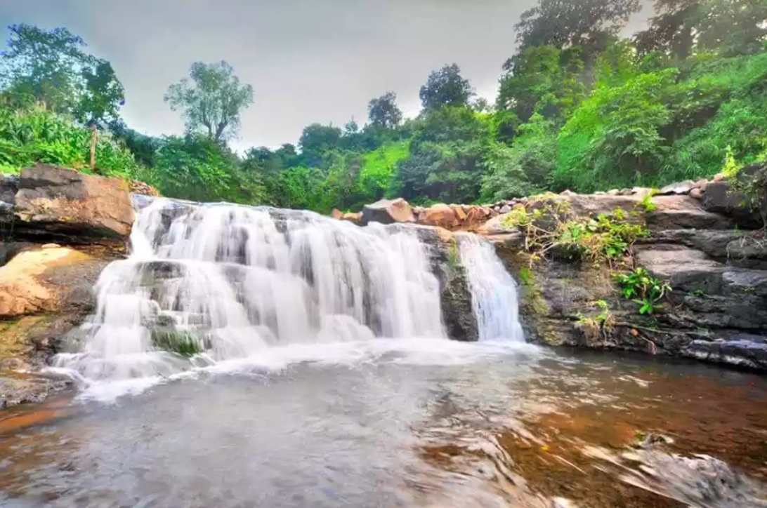 Side view of Zarwani Waterfall with lush greenery and rocky terrain, a popular eco-tourism destination in Dhirkhadi Side view of Zarwani Waterfall with lush greenery and rocky terrain, a popular eco-tourism destination in Dhirkhadi